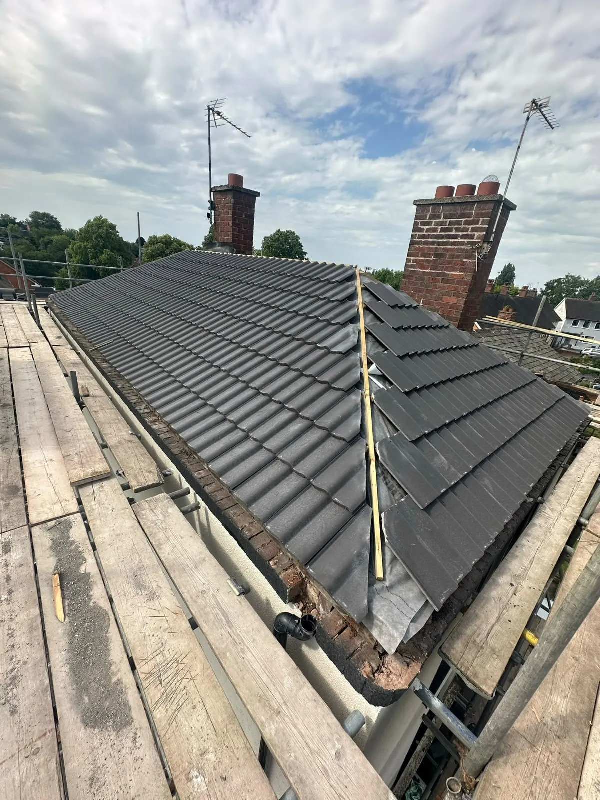 Newly tiled pitched roof with a brick chimney