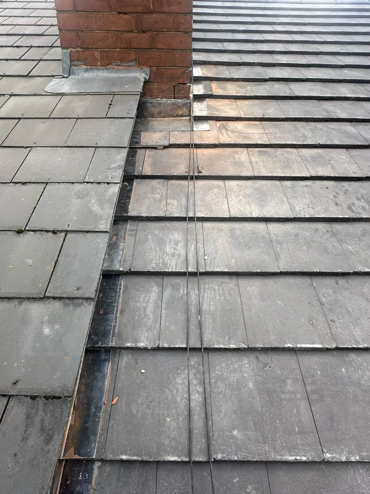 Grey roof tiles with lead flashing around a chimney