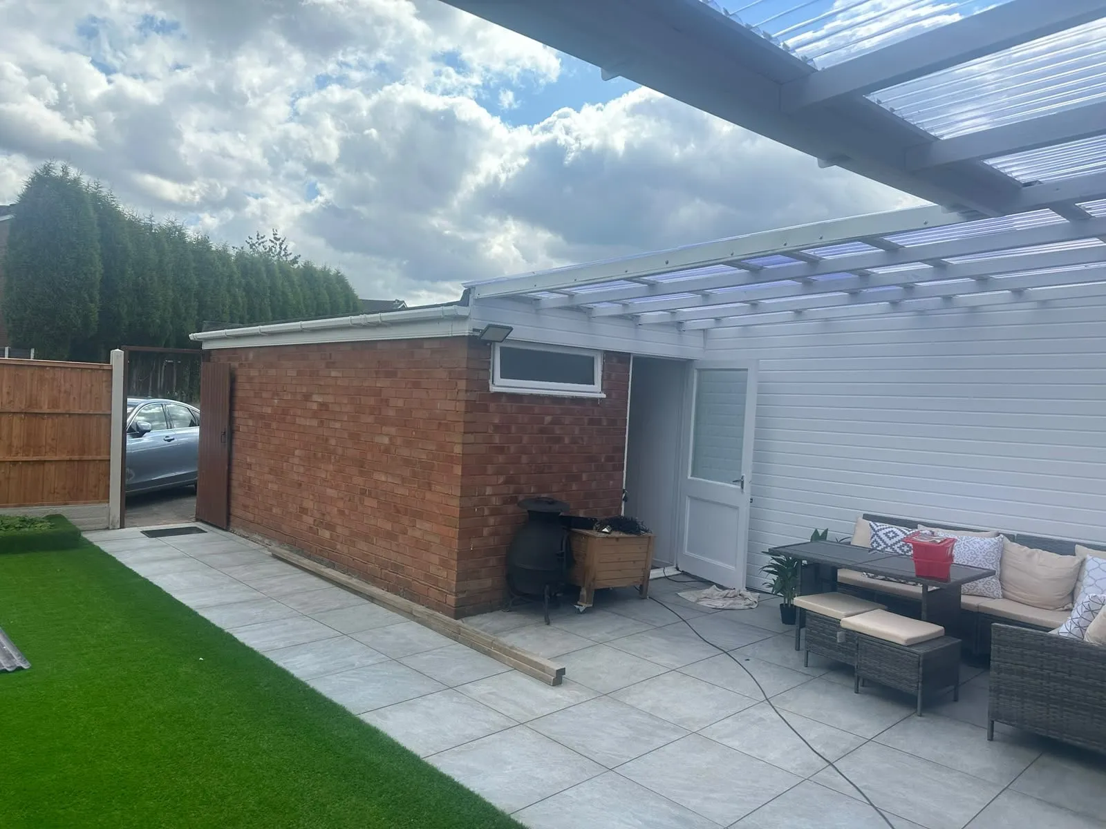 Pergola with a clear polycarbonate roof over a stone patio